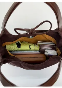 Top view showing the spacious yellow fabric interior of a brown suede bucket bag with essentials