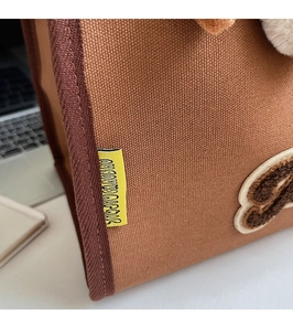 Détail du cabas en toile marron avec broderie de lettres en peluche et texture