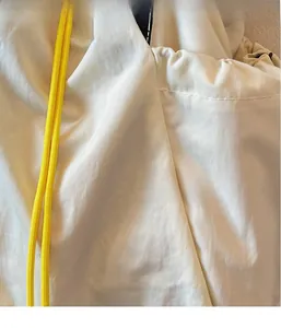 Detail of light beige breathable nylon fabric with a bright yellow drawstring closure