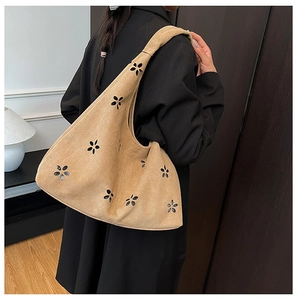 Detail of khaki suede tote bag featuring laser-cut floral patterns and a wide shoulder strap