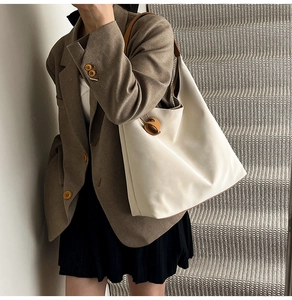 Detail of minimalist cream leather tote bag with brown straps worn on the shoulder