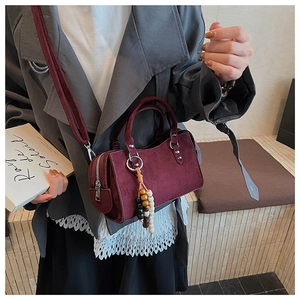 Détail du sac cylindrique en daim bordeaux avec pompon perlé et zip argenté