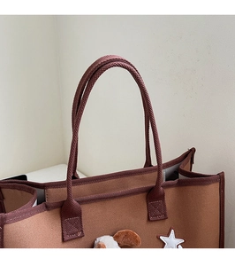 Détail du sac cabas en toile marron avec poignées renforcées et écusson étoile brodé