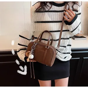 Detail view of brown frosted leather Boston bag with a mini baseball keychain accessory