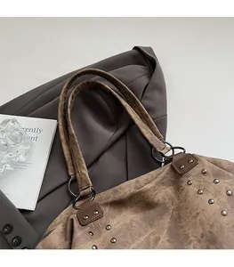 Detail of vintage brown suede shoulder bag featuring metal studs and silver ring accents