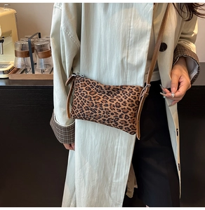 Close-up of leopard print crossbody bag with metal zipper and brown leather strap