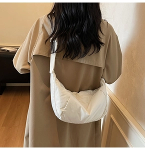 Close-up of white crescent crossbody bag with adjustable wide fabric strap on model