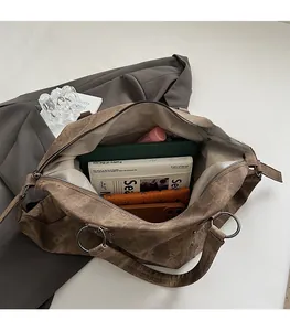 Detail view of a spacious vintage brown tote bag filled with a tablet, books, and wallet