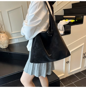 Detail view of large black matte tote bag with gold lettering shown on model