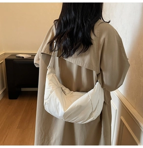 Rear view of model wearing a stylish white nylon crescent crossbody bag in a minimalist room