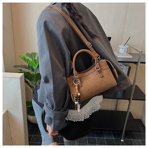 Détail du sac à main en daim marron avec pendentif en bois vintage et double poignée