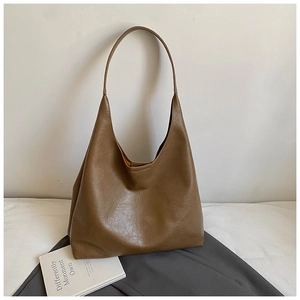 Détail de la texture en cuir marron foncé et de la doublure jaune de ce grand sac hobo