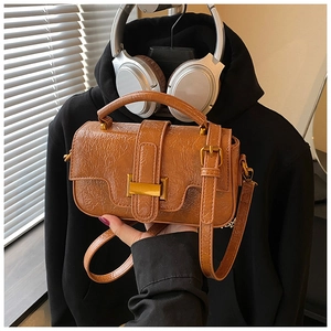Macro detail of brown textured leather handbag with vintage gold metal clasp and top handle