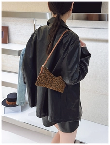 Detail view of stylish leopard print shoulder bag with brown leather strap and metal hardware