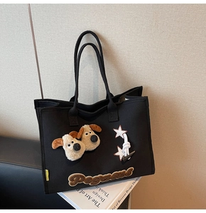 Détail du sac cabas en toile noire avec des têtes de chiots en peluche et des étoiles