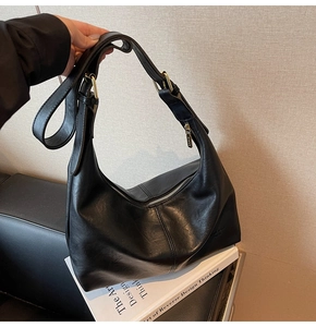 Detailed macro view of black leather hobo bag texture and elegant gold metal buckles