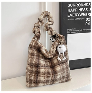 Détail d'un sac cabas en peluche à carreaux avec poignée froncée et breloque blanche
