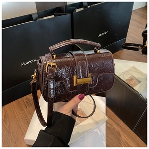 Detail of dark brown oil-wax leather handbag with golden buckle and adjustable strap