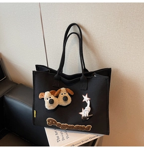 Détail du sac cabas en toile noire avec chiens en peluche 3D et étoiles sur canapé cuir