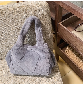 Close-up of grey faux fur tote bag featuring a 3D diamond quilted pattern on a sofa