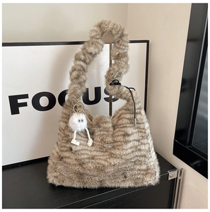 Detail of grey striped faux fur tote bag featuring a cute white plush monster charm