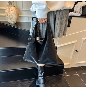Detail of minimalist black hobo tote bag in matte synthetic leather with logo