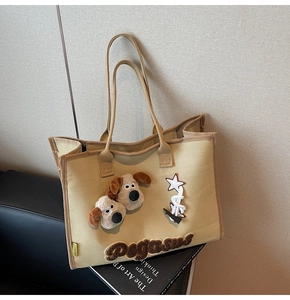 Détail d'un cabas en toile kaki avec breloques de chiots en peluche et broderie Pegasus