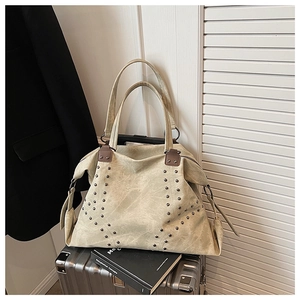 Detail of vintage beige tote bag with rivets placed on a silver suitcase for travel