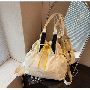 Detail of cream canvas tote bag with bright yellow drawstring and striped woven handle