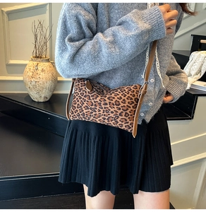 Detail of leopard print crossbody bag with brown leather strap on model's shoulder