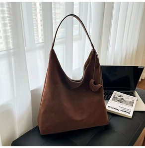 Detailed close-up of brown suede hobo tote bag with soft minimalist shoulder strap