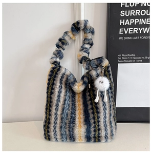 Détail du sac cabas en peluche rayé avec un joli pendentif monstre blanc