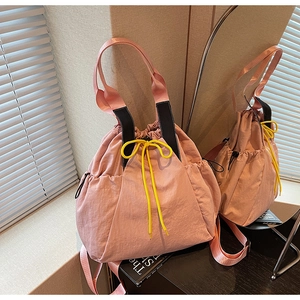 Pink drawstring tote bag featuring contrasting yellow cords and versatile straps