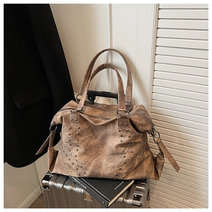 Macro detail of vintage brown leather tote bag featuring metal rivets and textured finish