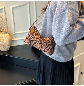 Detailed close-up of leopard print shoulder bag with brown leather strap and zip detail