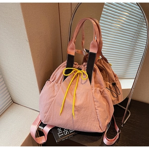 Detail of pink nylon drawstring tote bag featuring black handles and neon yellow cords