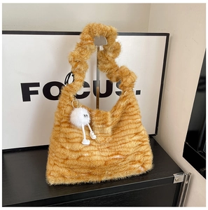 Detail of yellow fuzzy tote bag with striped texture and cute monster plush charm