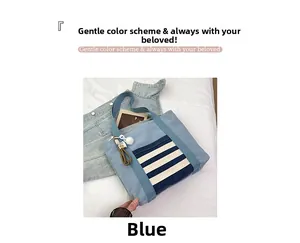 Detail shot of blue denim tote bag featuring striped front pocket and white fur ball charm