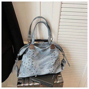 Detail of vintage blue tote bag featuring studded metal accents and retro washed texture