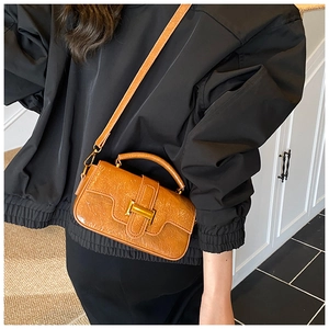 Detail of glossy pleated leather handbag in orange-brown with golden H-buckle hardware