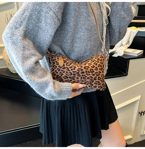 Detail of leopard print crossbody bag featuring brown strap and sleek zipper closure