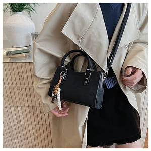 Détail d'un sac bandoulière vintage noir avec rivets argentés et perles en bois