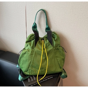 Detail view of green nylon drawstring bucket bag with yellow contrast cords and durable straps