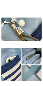 Close-up of blue striped canvas tote bag with side pocket and plush pompom charm