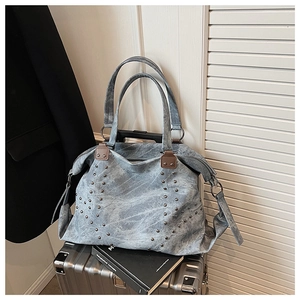 Detail of vintage gray washed tote bag with metal studs placed on a silver suitcase