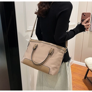 Détail d'un sac cabas kaki avec garniture en cuir marron et bandoulière réglable