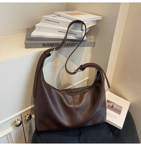 Detailed close-up of a vintage dark brown leather hobo bag on a textured surface