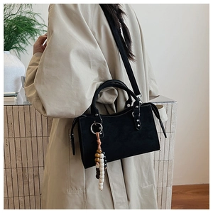 Détail d'un sac à main noir mat avec perles en bois et large bandoulière en nylon