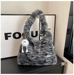 Detail of plush tiger print tote bag with a cute white cartoon monster charm attached