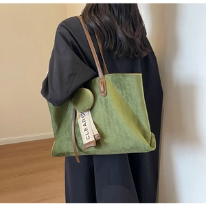 Detail of green quilted suede tote bag with brown leather strap and clear tag charm